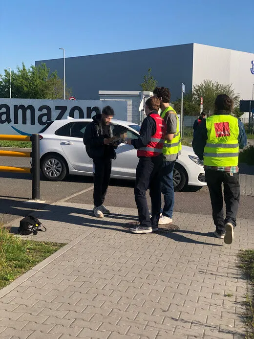 Mitarbeiter verteilen Flyer vor Amazon.