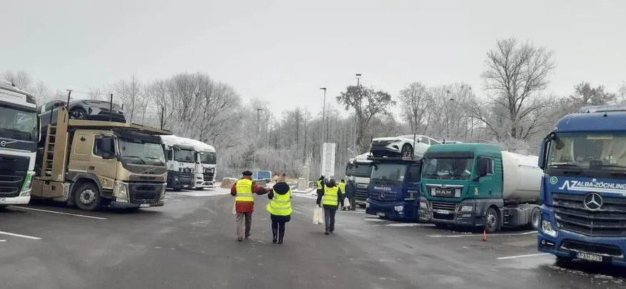 Mitarbeiter verteilen Flyer zu Arbeitsausbeutung an LKW Fahrer auf Parkplatz.